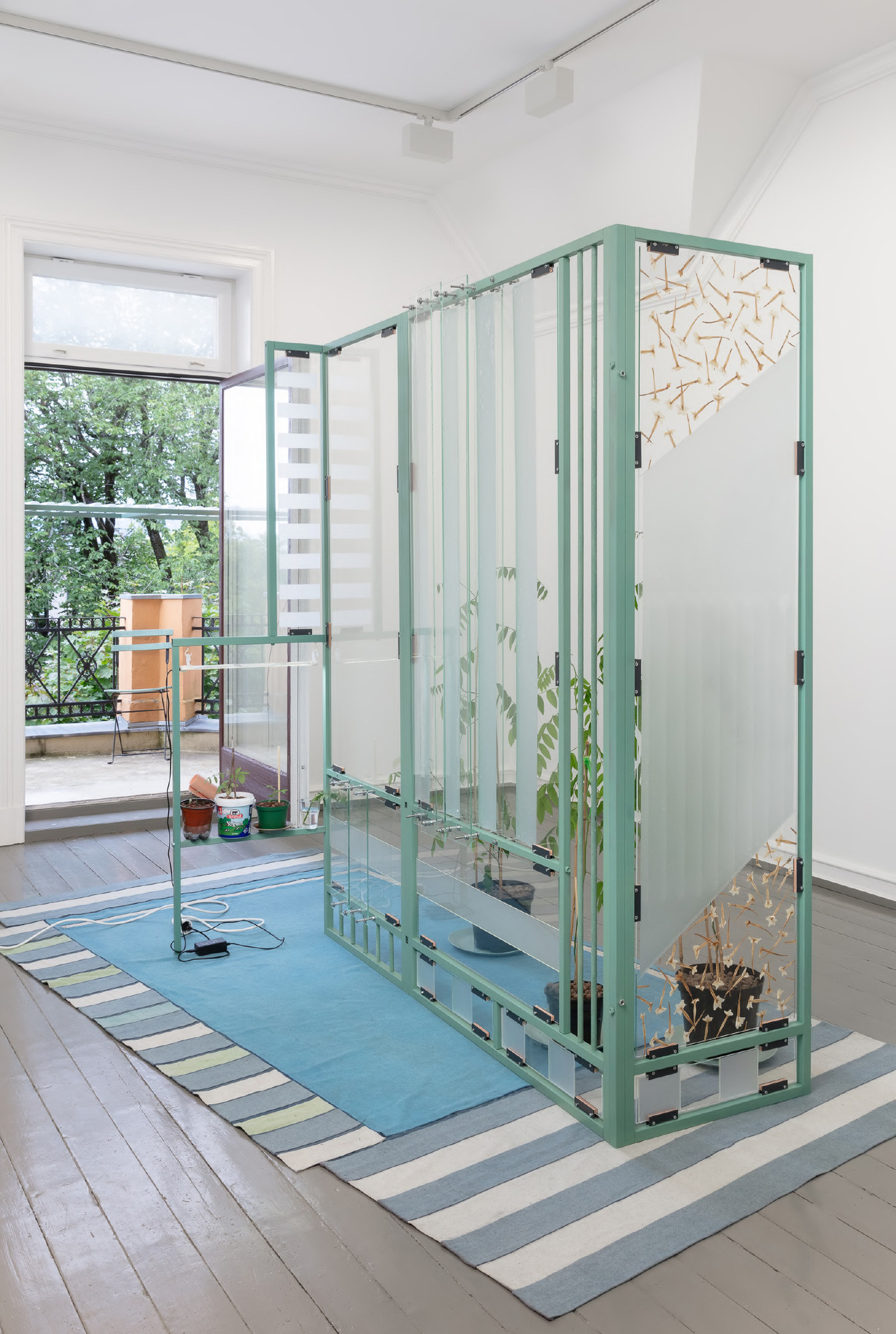 sjuende som selvisk form,
Norsk Billedhoggerforening,
2023. Woodland tobacco (Nicotiana Sylvestris) collected from Lakkegata, Oslo, through nightly walks June-September 2022, lacquered steel, engraved glass, wax, pigment, window foil, sand, copper, PVC hose, EVA foam, LED growth-light, indigo (Indigofera Tinctoria), hand colored wool (indigo), hand colored wool (pigment, ink, bleach, pencil), all weather jacket, glue, embroidered name tag, found ceramic plates. Photo: Tor S. Ulstein